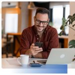 Person smiling in a cafe looking at their phone